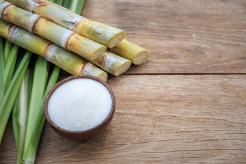Obraz na płótnie Canvas Top view white sugar and sugar cane and leaf on wooden