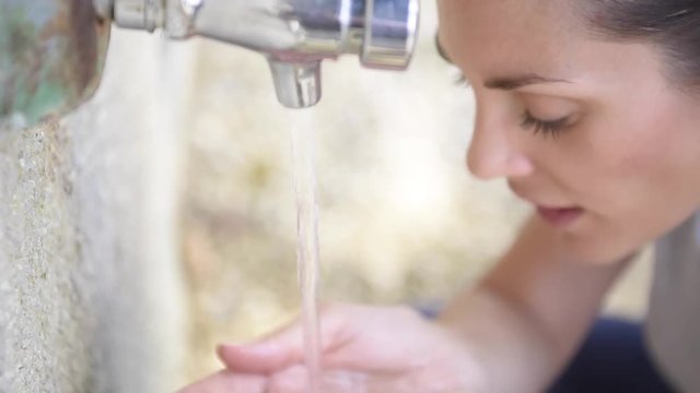 Portrait of girl drinking water from faucet