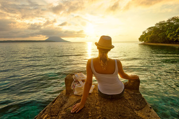 woman backpacker sitting on pier and enjoying sunset
