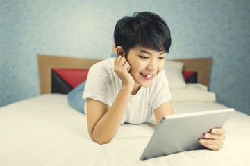 Woman using digital tablet on bed vintage tone.