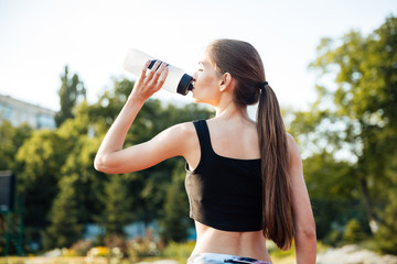Female athlete drinking from water bottle after workout at stadium