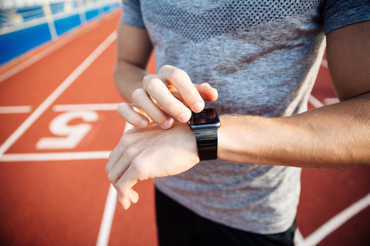 Cropped image of a young muscular man adjusting smart watch