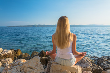 Fototapeta na wymiar young beautiful woman meditation on beach in lotus position