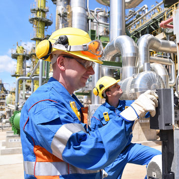 Industriearbeiter mit Schutzausrüstung in einer Raffinerie bedient Anlage // Industrial workers with protective equipment in a refinery operated facility