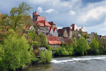 Riverside with historical landmarks, towers, half-timbered houses and trees on the background the...