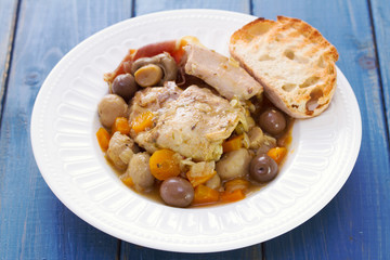 rabbit stew with mushrooms and carrot on white dish on blue wooden background