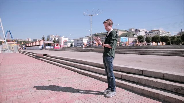Young tourist man using map on his tablet walking in the city. HD.