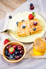 Waffles with berries on wooden background