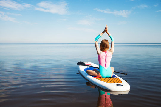 Woman doing yoga on sup board with paddle