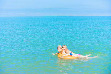 Happy mother and son swimming on yellow rubber ring  in the sea.