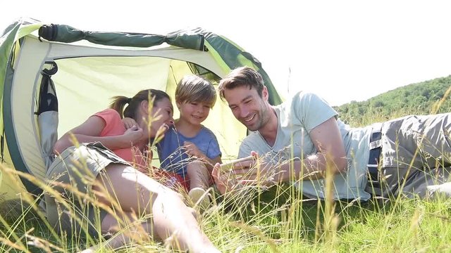 Family in camping tent playing with smartphone