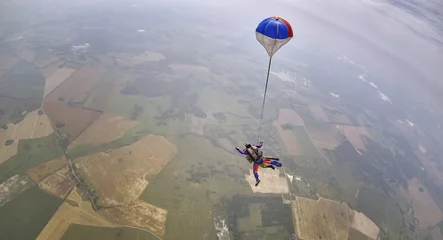 Papier Peint photo Sports aériens Skydiving tandem parachute above the countryside