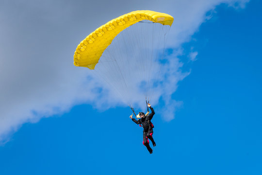 Skydiver in the air under the yellow canopy