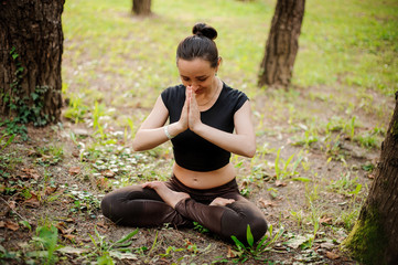 Portrait of smiling beautiful sporty young woman working out in park alley, standing with palms touching in Namaste gesture