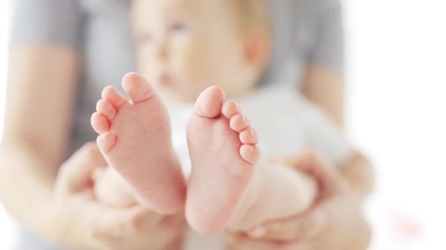 mother holding little baby with bare feet at home 19