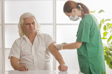 Portrait of doctor / nurse giving injection to senior man. Healthcare, medicine and elderly concept 