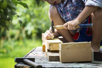 Boy learns to hammer nails in a garden