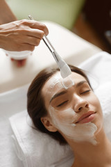Facial Beauty Treatment. Beautiful Woman Getting Cosmetic Mask