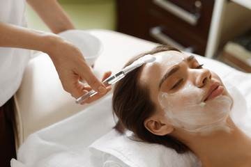 Obraz na płótnie Canvas Facial Beauty Treatment. Beautiful Woman Getting Cosmetic Mask