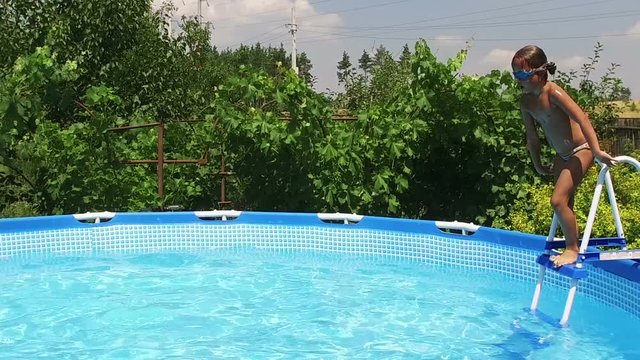 Weekend. Swimming pool. Little girl jumping into the water in pool. Slow motion. HD