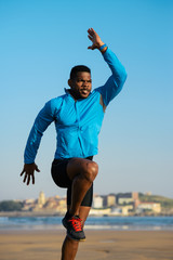 Runner doing power skips jumping exercise for warming up before running workout at the beach.