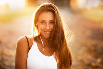 Junge hübsche Frau hört Musik bei Sonnenuntergang und ist glücklich und lacht