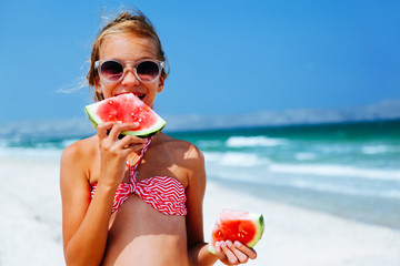 Child eating watermelon on the beach
