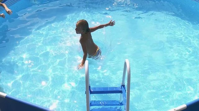 Weekend. Swimming pool. Little girl jumping into the water in pool. Slow motion. HD