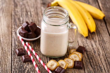 Banana smoothie  with chocolate in glass jar with drinking straw