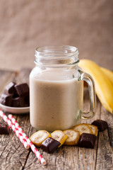Banana smoothie  with chocolate in glass jar with drinking straw