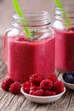 Summer smoothie in glass jar with berries plates.