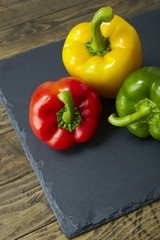 Colorful sweet bell peppers on a rustic slate and wooden table top background