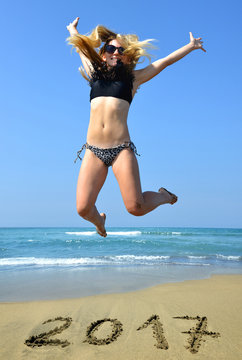 Young happiness woman jumping high by the sea while celebrating New Year 2017.