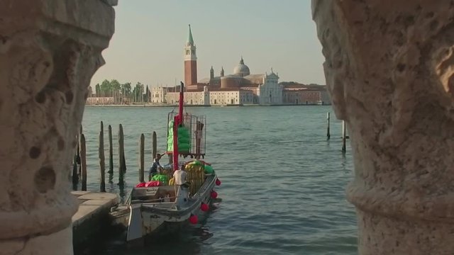 VENICE, ITALY - JUNE 19, 2016: Parking gandolas on the Doge's palace embankment with the bell tower of the Saint Giorgio Maggiore church view, Venice, Italy.