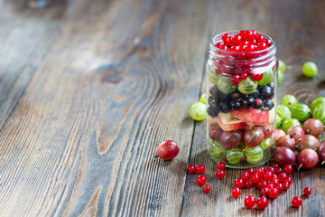 Summer berries smoothie in mason jar on rustic wooden table