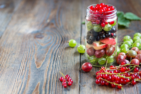 Summer berries smoothie in mason jar on rustic wooden table