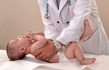 Pediatra examinando a un bebe.en el consultorio. - obrazy, fototapety, plakaty