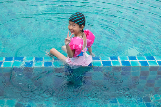 Happy little girl plaing in swimming pool