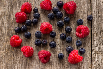 Raspberries and blueberries on a wooden background