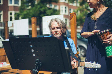 Street musicians performing acoustic in summertime at outdoor ca