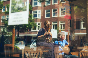 Window reflections of musicians performing acoustic at outdoor c