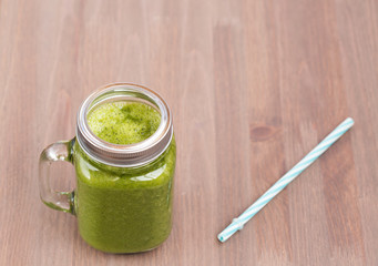 A green smoothie in a mason jar on wooden background