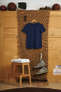 BNavy blue basic cotton t-shirt presented in rustic interior, white folded shirts on small wooden stairs below