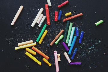 Colorful pastel crayon oil colors on chalkboard or black paper