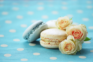 Fototapeta na wymiar dessert macaroon and delicate pastel roses on a bright blue tablecloth with white polka dots 
