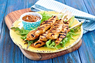 homemade chicken kebabs on wooden skewers with lettuce and peanut sauce
