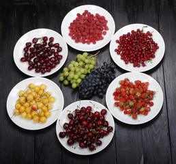  berries in plates on wooden background