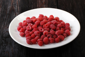 raspberry in plate on wooden background
