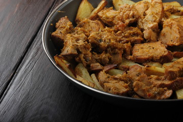 fried meat in frying pan on wooden background