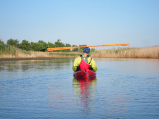 Greenland wooden paddle on the head of man in red kayak in summer on river. Zen Meditation
